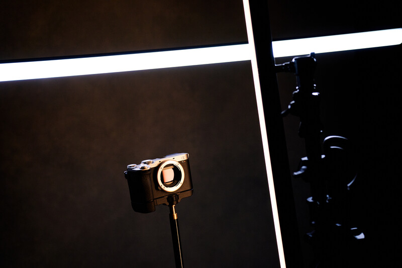 Ring light mounted on stand in dark studio setup with equipment visible in background.