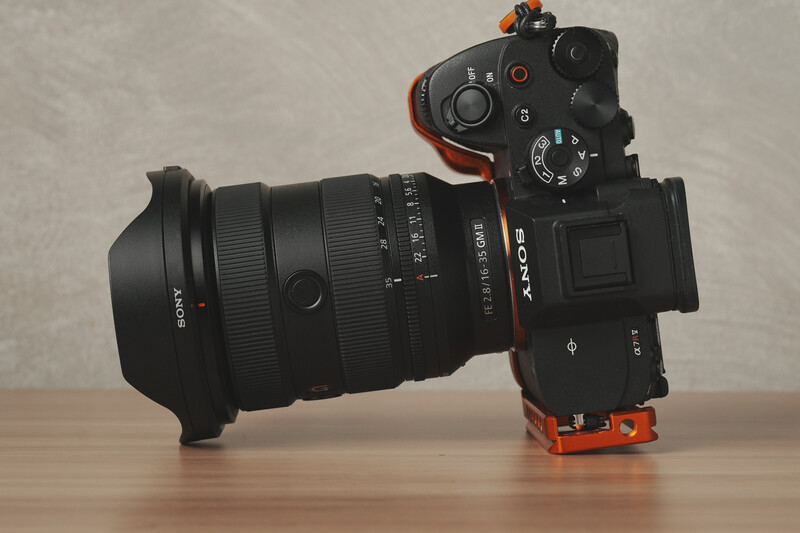 Sony mirrorless camera with wide-angle lens mounted, displayed on wooden surface against neutral background.