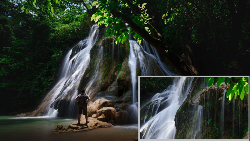 Multi-tiered waterfall cascading over moss-covered rocks into a calm pool, surrounded by lush green foliage.