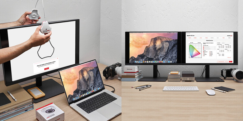 Creative professional's desk workspace with dual monitors, laptop, and designer holding a pendant light fixture.
