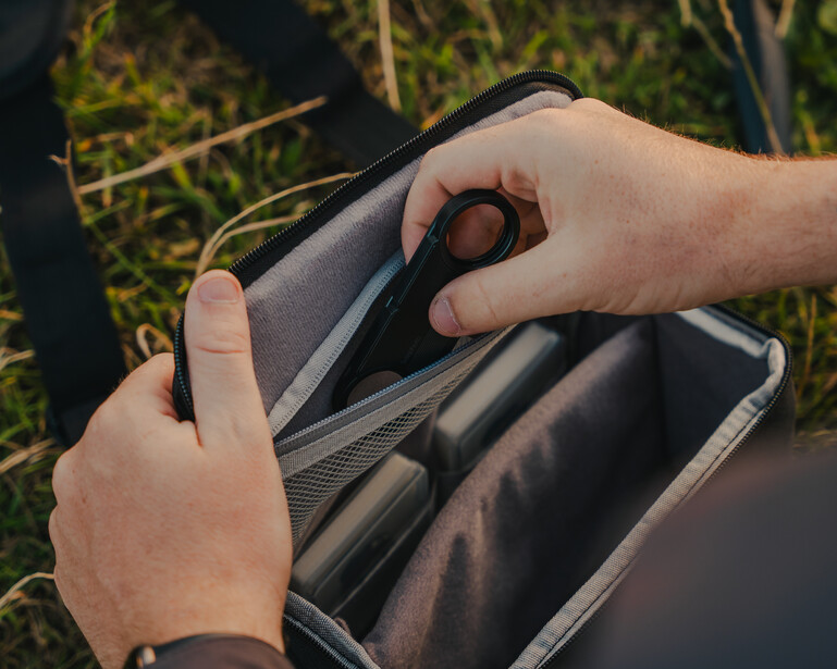 Photographer's hands opening an empty wallet over a grassy outdoor setting.