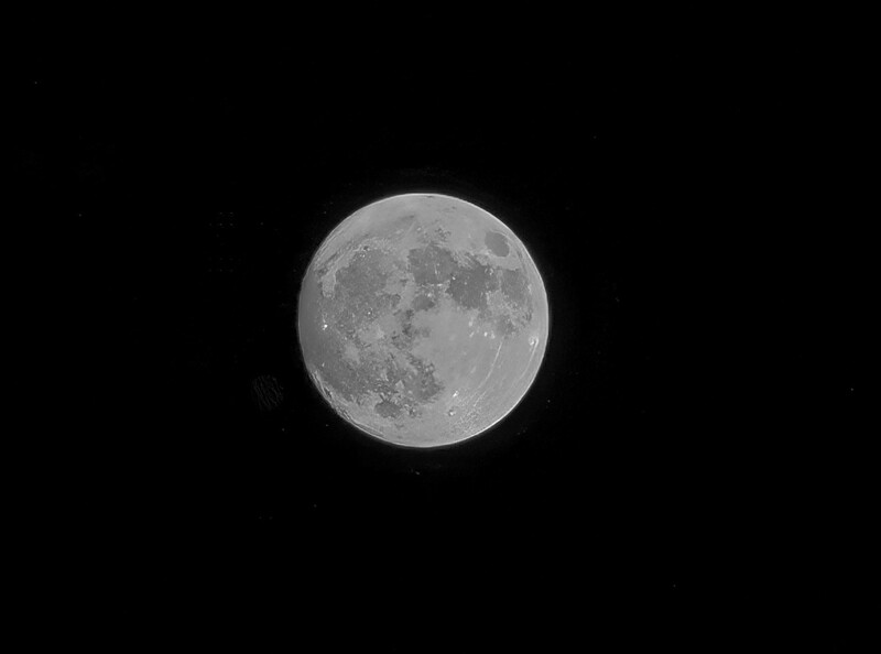 Full moon centered against black sky, showing detailed lunar surface features and craters.