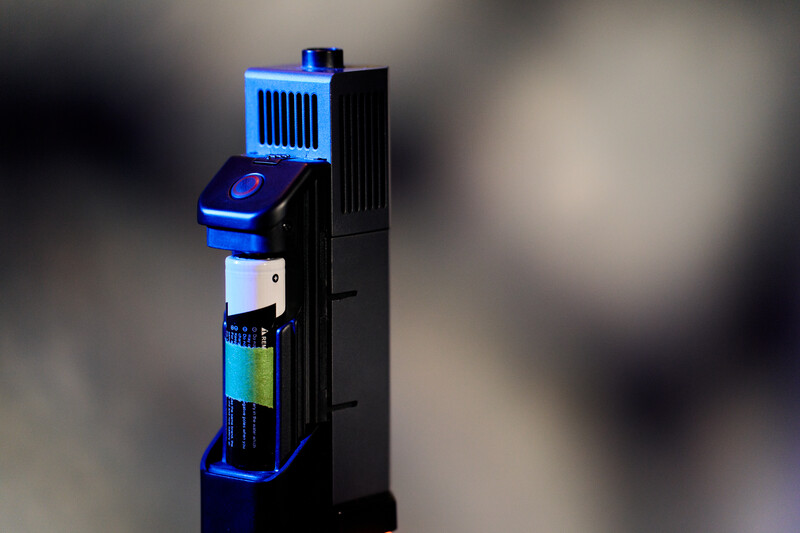 Tall cylindrical black device with blue accent lighting and illuminated blue grille at top.