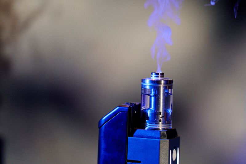 Blue lighter with flame and electric plasma effect against blurred background.