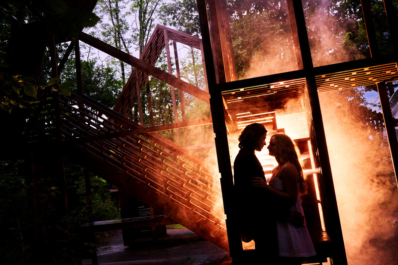 Two silhouetted figures stand in a glowing doorway with dramatic golden light pouring through the frame.