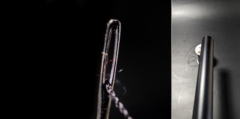 Close-up of a curved metal tube with water droplets against dark background, lit dramatically from the side.