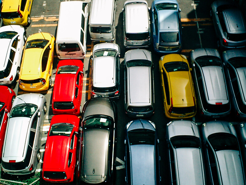 Aerial view of densely packed cars in a parking lot arranged in tight rows.