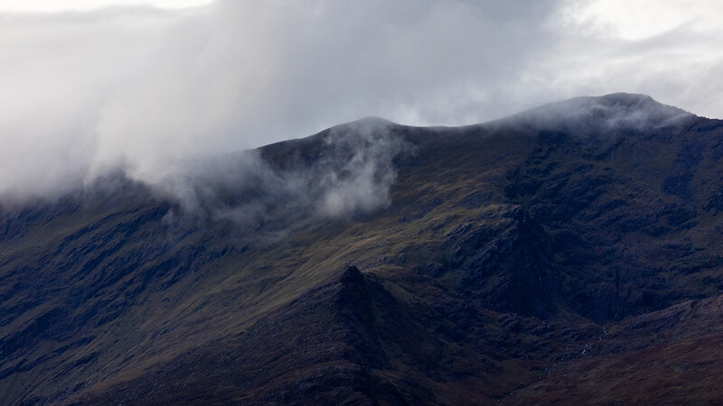 Mountain landscape with volcanic slopes shrouded in low clouds and mist.