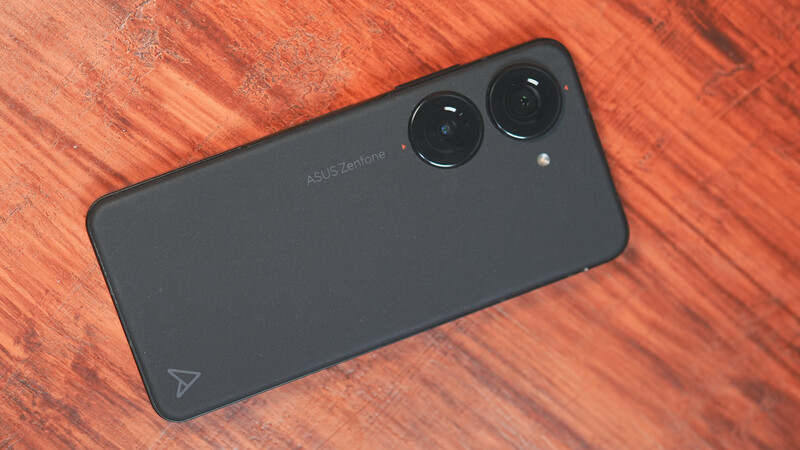 ASUS Zenfone smartphone with dual rear cameras on warm wood surface.