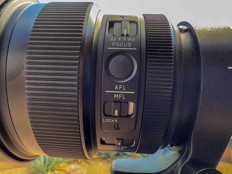 Close-up of a camera lens showing focus ring, AFL/MFL switches, and focus mode controls.