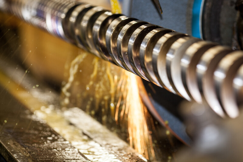 Close-up of a lathe cutting tool with spiral flutes creating wood shavings during machining.