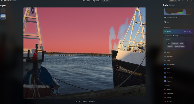 Golden hour light illuminates a large cargo ship and industrial bridge structure reflected in calm water.