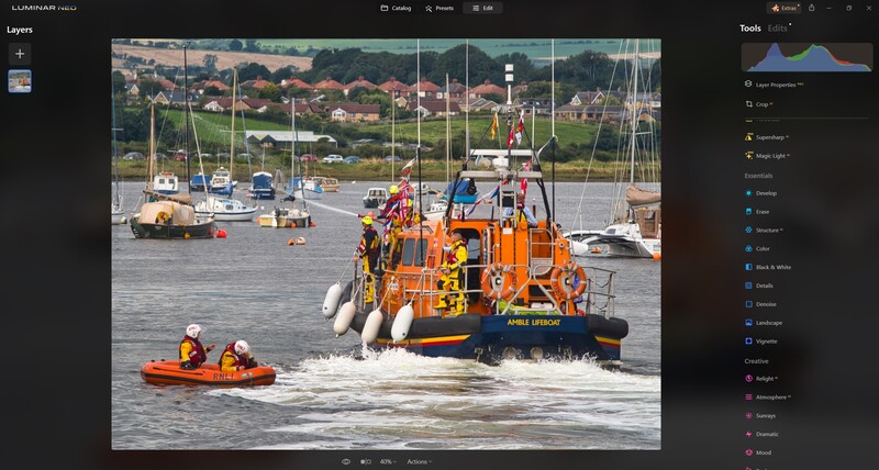 Orange lifeboat with crew members operating rescue equipment near inflatable rescue boat in harbor waters.
