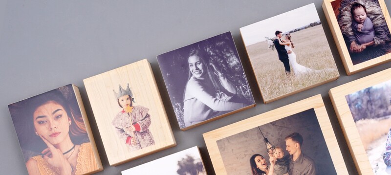 Collection of wooden-framed photo prints arranged on gray background showing various portraits and scenes.
