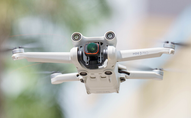 DJI Mini 3 Pro drone photographed head-on against a blurred outdoor background.