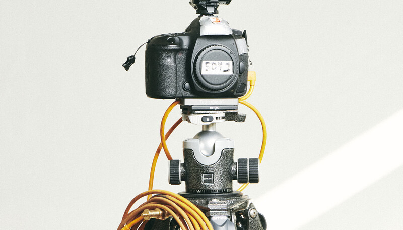 Professional camera rig with DSLR body mounted on gimbal stabilizer with orange cable coiled below.