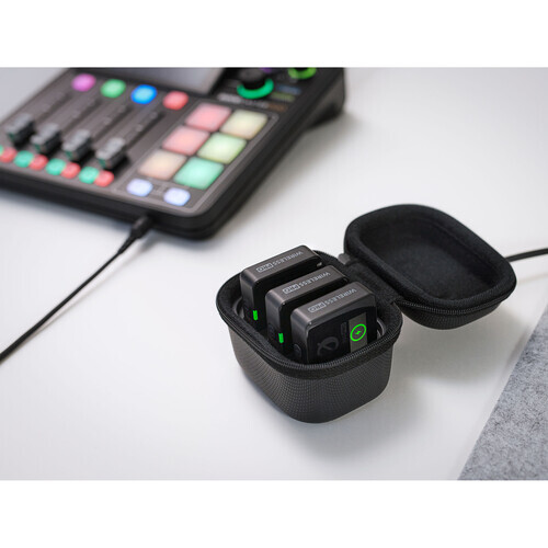 Black carrying case with green accents containing audio equipment modules, positioned next to a production controller.