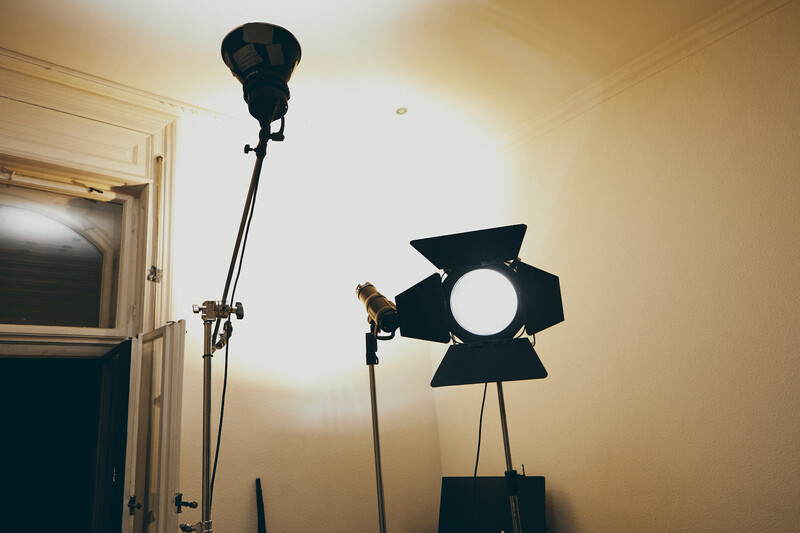 Professional film lighting setup with a large Fresnel light fixture and smaller key light mounted on stands in a studio space.