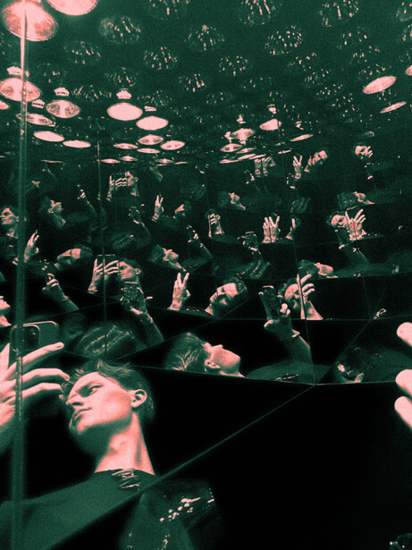 Crowd of people with hands raised in a concert or event venue with green and pink lighting.