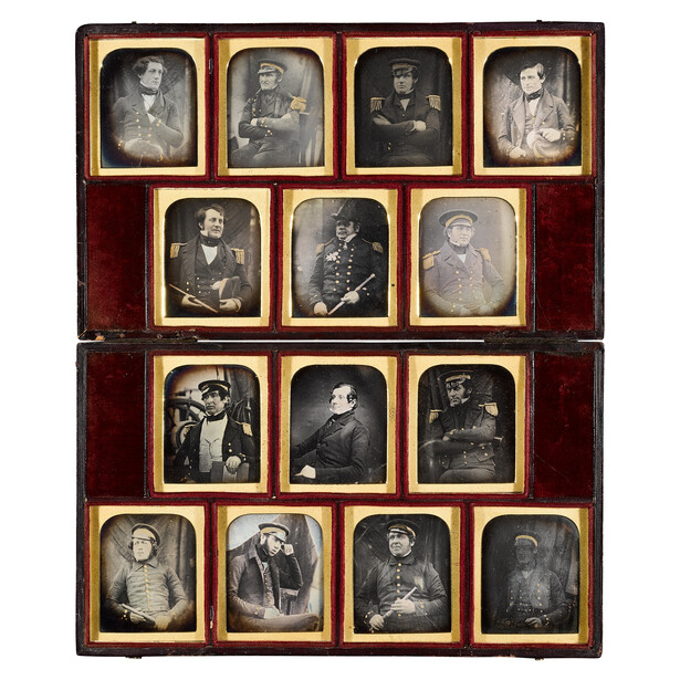 Daguerreotype case displaying fourteen portrait photographs arranged in wooden frame with red velvet backing.