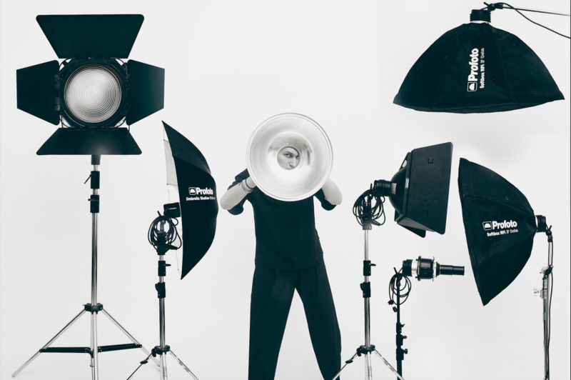 Studio lighting kit with four professional strobes mounted on stands and light modifiers arranged symmetrically.