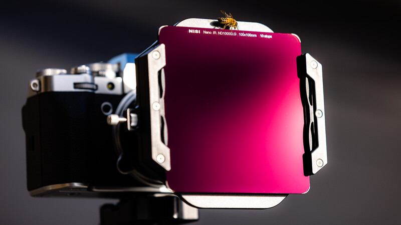 Large format camera with magenta gel filter attached to lens assembly.
