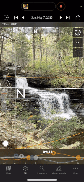 Multi-tiered forest waterfall flowing over moss-covered rocks surrounded by spring foliage