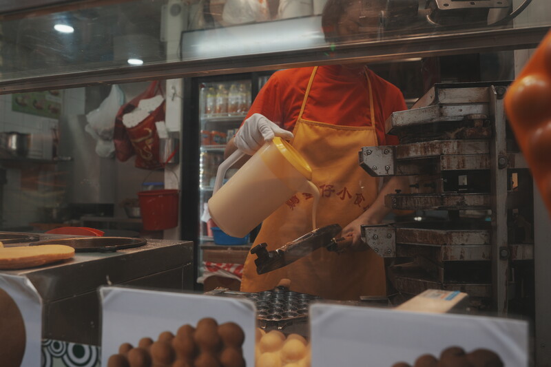 Vintage toy cowboy figure positioned in storefront window display with product boxes below.