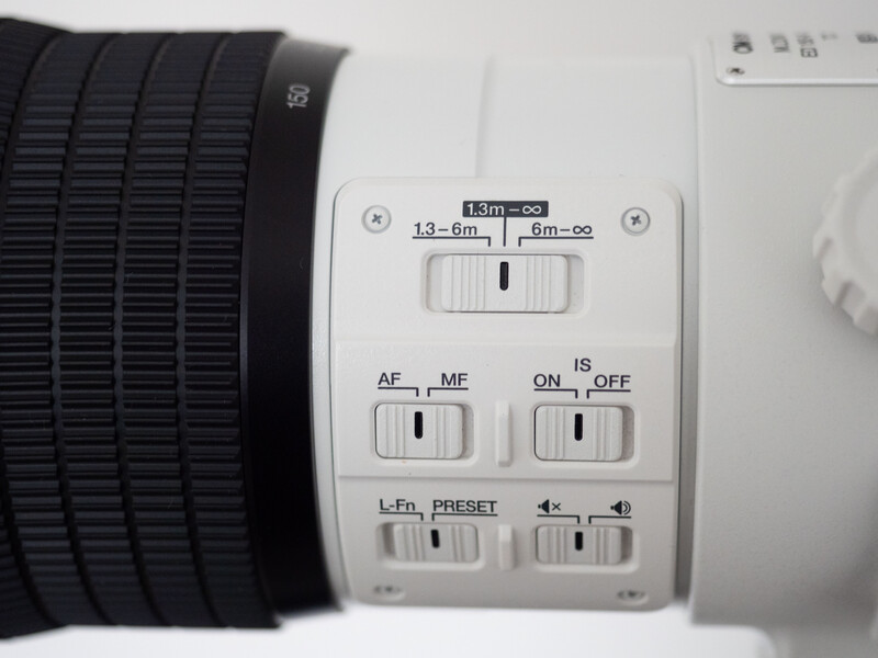 Close-up of a telephoto lens control panel with manual focus ring, autofocus and manual mode switches, and preset buttons.