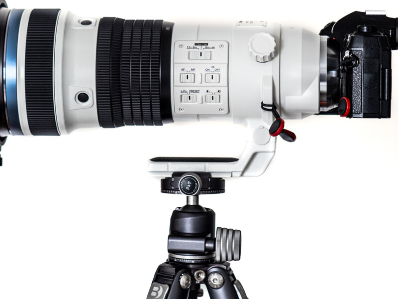 White telephoto lens mounted on tripod with ball head, shown from above in overhead view.
