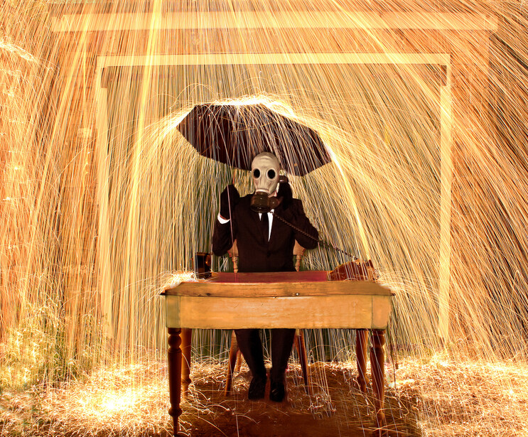 Skeleton in formal attire seated at a wooden desk under an umbrella, surrounded by falling light streaks.