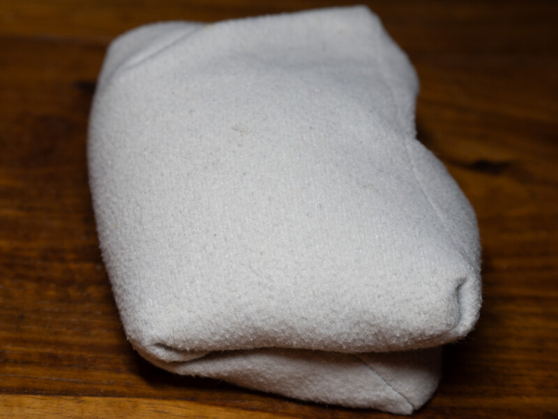 Crumpled white cloth or fabric bunched on a dark wood surface.