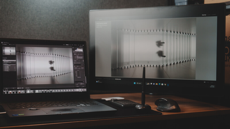 Dual-monitor photography editing setup displaying architectural radiator image with post-processing software on laptop and large external display.