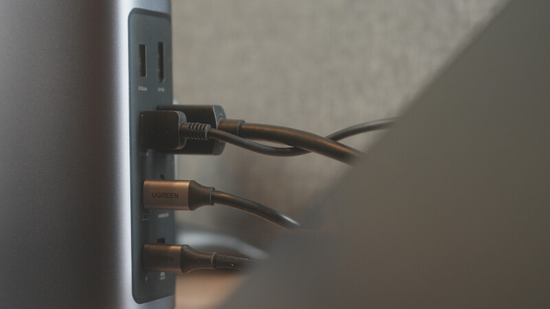 Three electrical cords plugged into a gray wall outlet, casting shadows on beige wall surface.