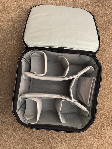 Open camera gear organizer with padded dividers and compartments for storing lenses and accessories.