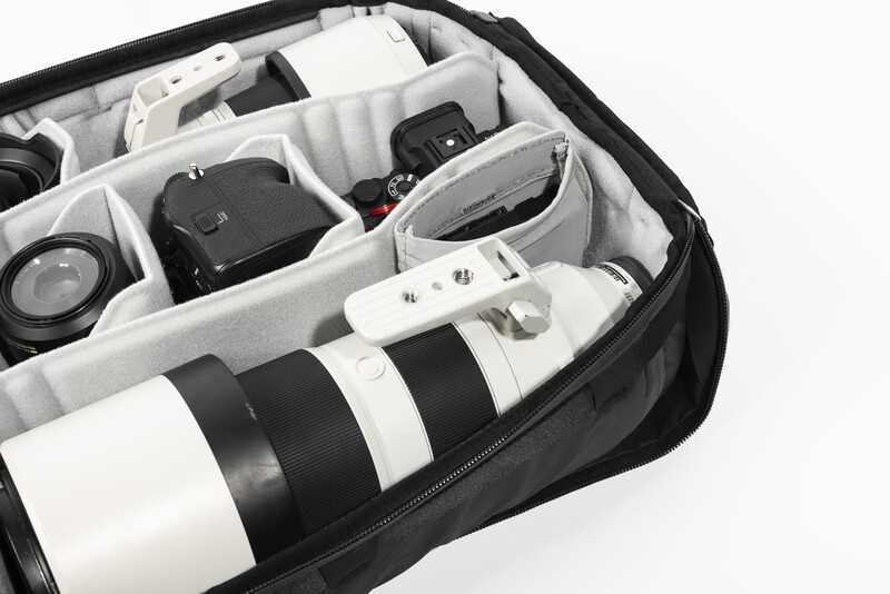 Camera bag interior with organized compartments holding lenses, camera body, and accessories.