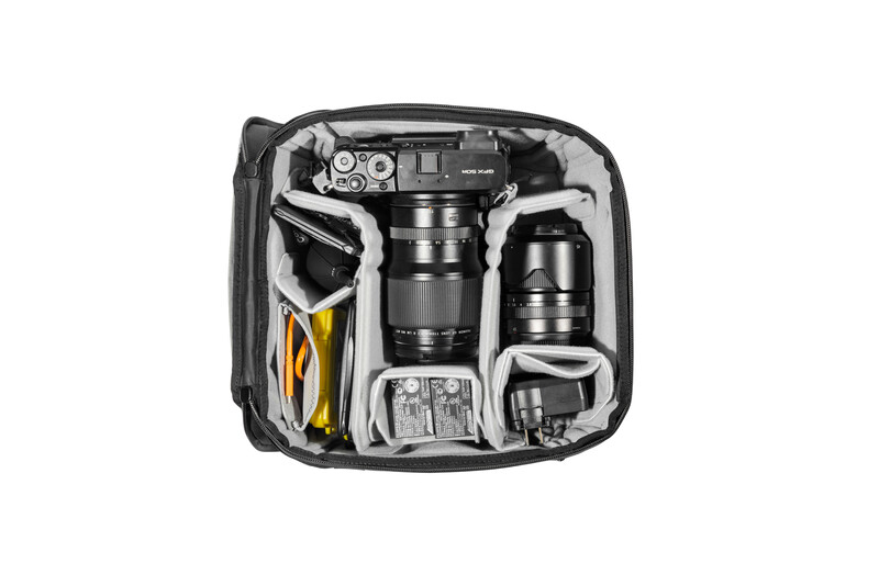 Overhead view of organized camera gear bag containing two camera bodies, multiple lenses, and accessories.