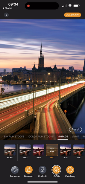City skyline at dusk with illuminated cathedral spire reflected in still water below light trails.