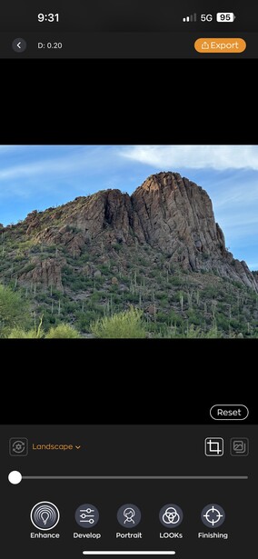 Rocky desert mountain peak with sparse desert vegetation under clear blue sky.