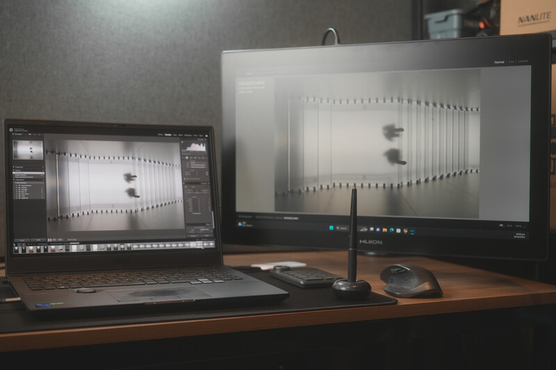 Photography editing workstation with laptop and external monitor displaying architectural interior images in post-processing software.