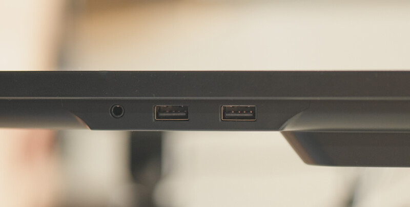 Close-up of monitor back panel showing power button and two USB ports against blurred background.