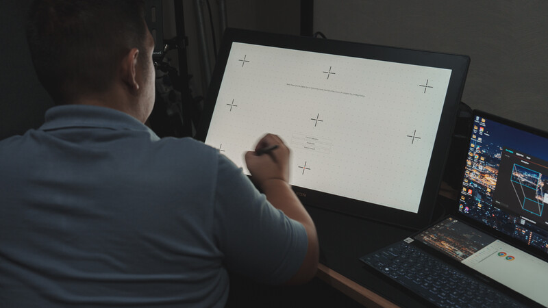 Photographer reviewing calibration chart on monitor with reference display visible.