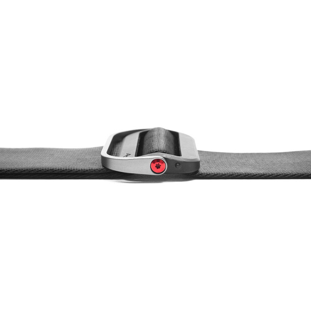 Minimalist product shot of a gray and silver wristband device with a red circular button against a neutral background.
