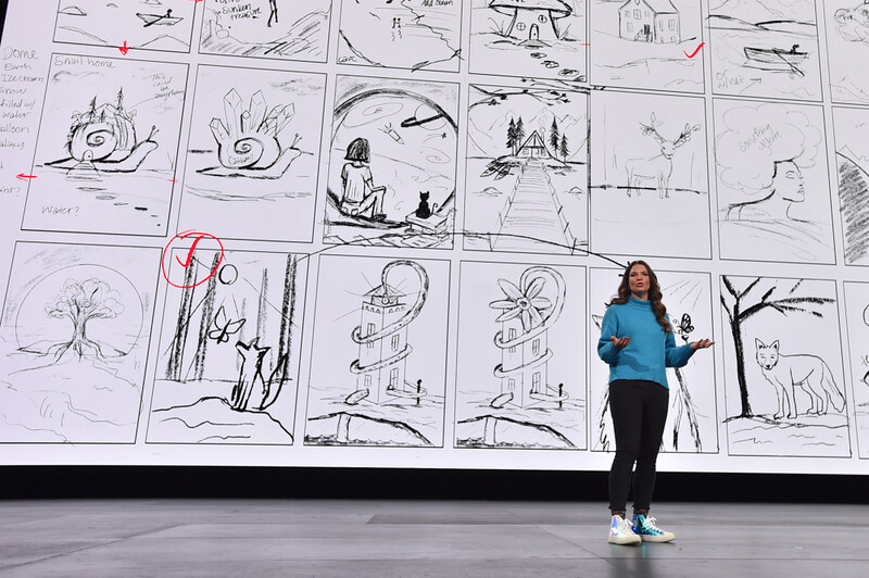 Woman onstage in front of a screen showing her artwork.