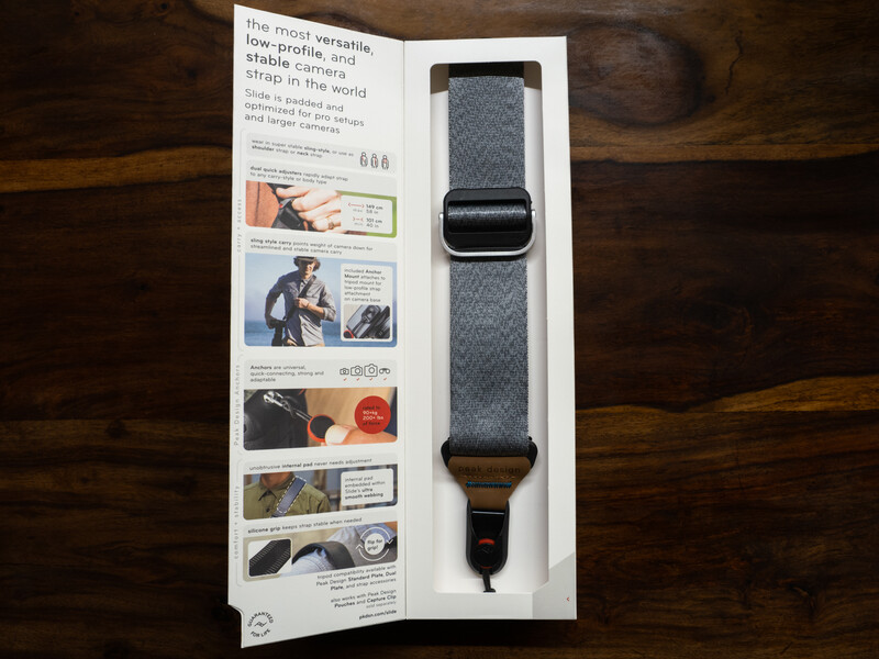 Camera strap packaging displayed open on wooden surface, showing product and instructional panels.