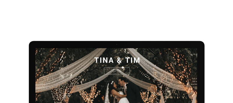 Bride and groom kissing under draped fabric with warm string lights overhead.