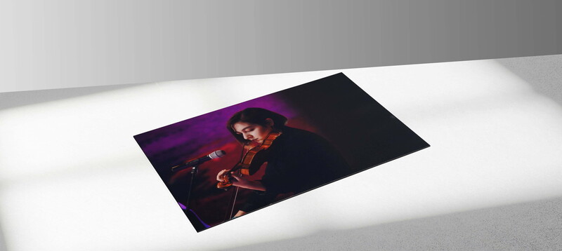 Portrait print displayed on white surface showing figure in red jacket against purple and black background.