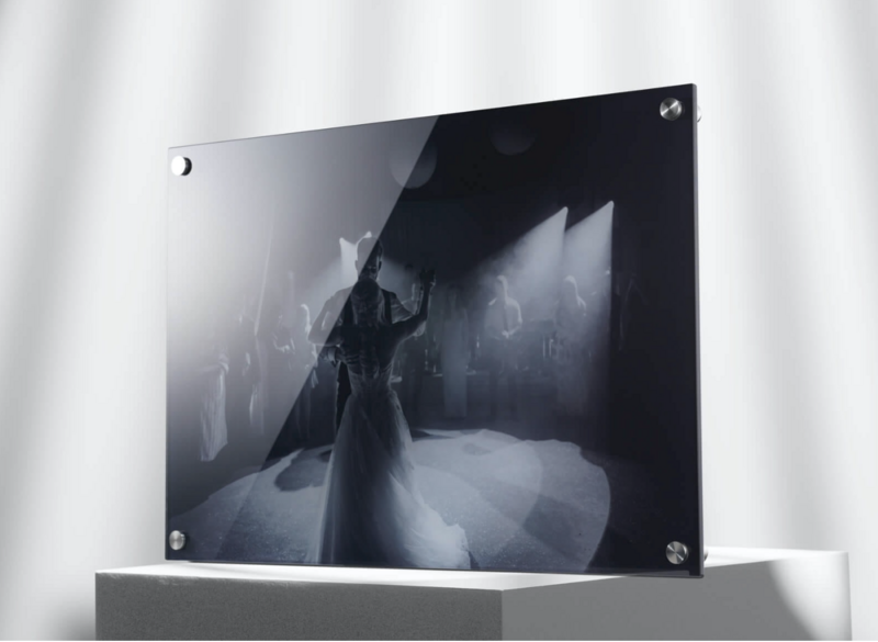 Black and white photograph mounted on acrylic sheet showing a figure in dramatic pose within an architectural interior.