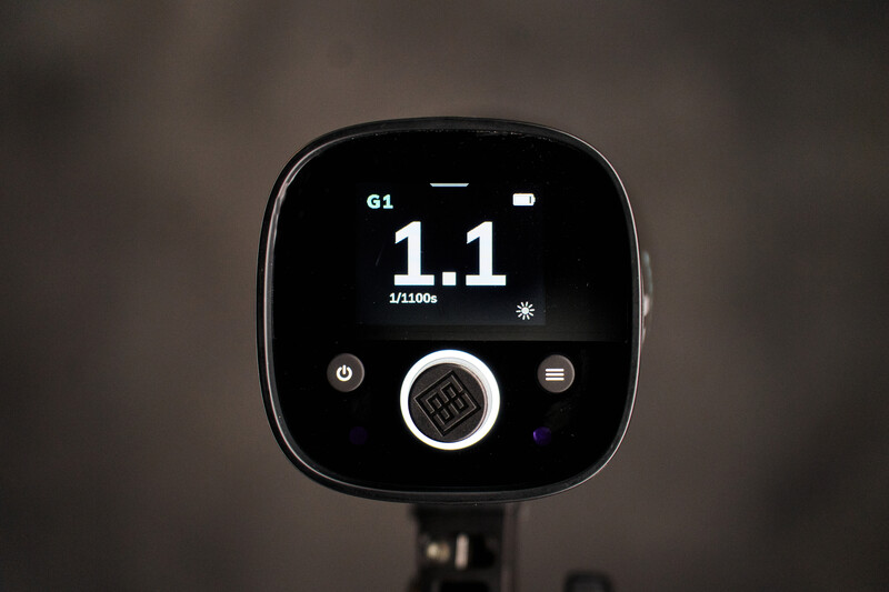 Close-up of a digital camera flash meter display showing a reading of 1.1 and 1/1000s shutter speed.