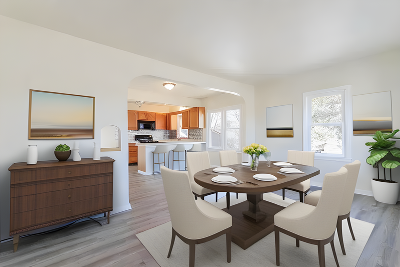 Modern open-concept dining and kitchen space with round pedestal table and cream upholstered chairs.